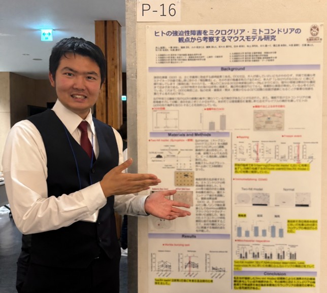 研究会会場で発表ポスターを紹介する井上さん