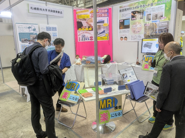 （有）北海化成工業所　代表取締役　伊吹敦氏（左）、製品開発部　櫻井美果氏（右）による「高さ調節できる腹部用MRIコイルサポート台」の製品説明