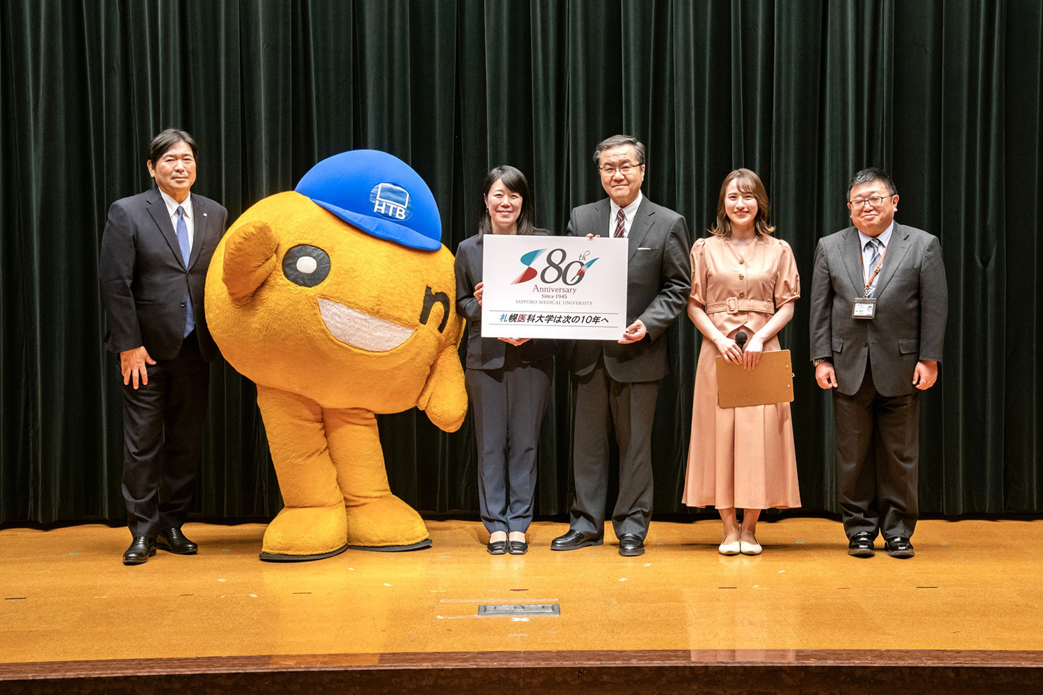 札幌医科大学･HTB包括連携協定事業「国際医療セミナー」_左からHTB齊木常務取締役、onちゃん、国境なき医師団日本 中嶋会長、山下学長、HTB 福永アナ、杉村教授 ©HTB